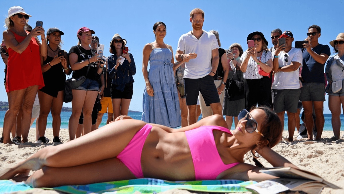 Unbothered Beachgoer Goes Viral for Continuing to Sunbathe Despite Crowd Surrounding Prince Harry and Meghan Markle