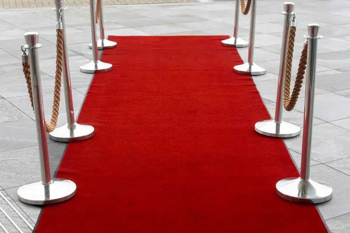 Illuminated theater marquee and red carpet entrance with photographers and crowds at night