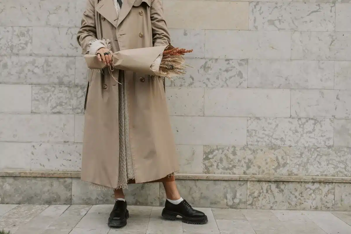 Person wearing a neutral coat and practical footwear walking through a city street