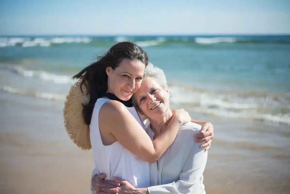 Mère et fille enlacées sur une plage ensoleillée, moment intime de vacances