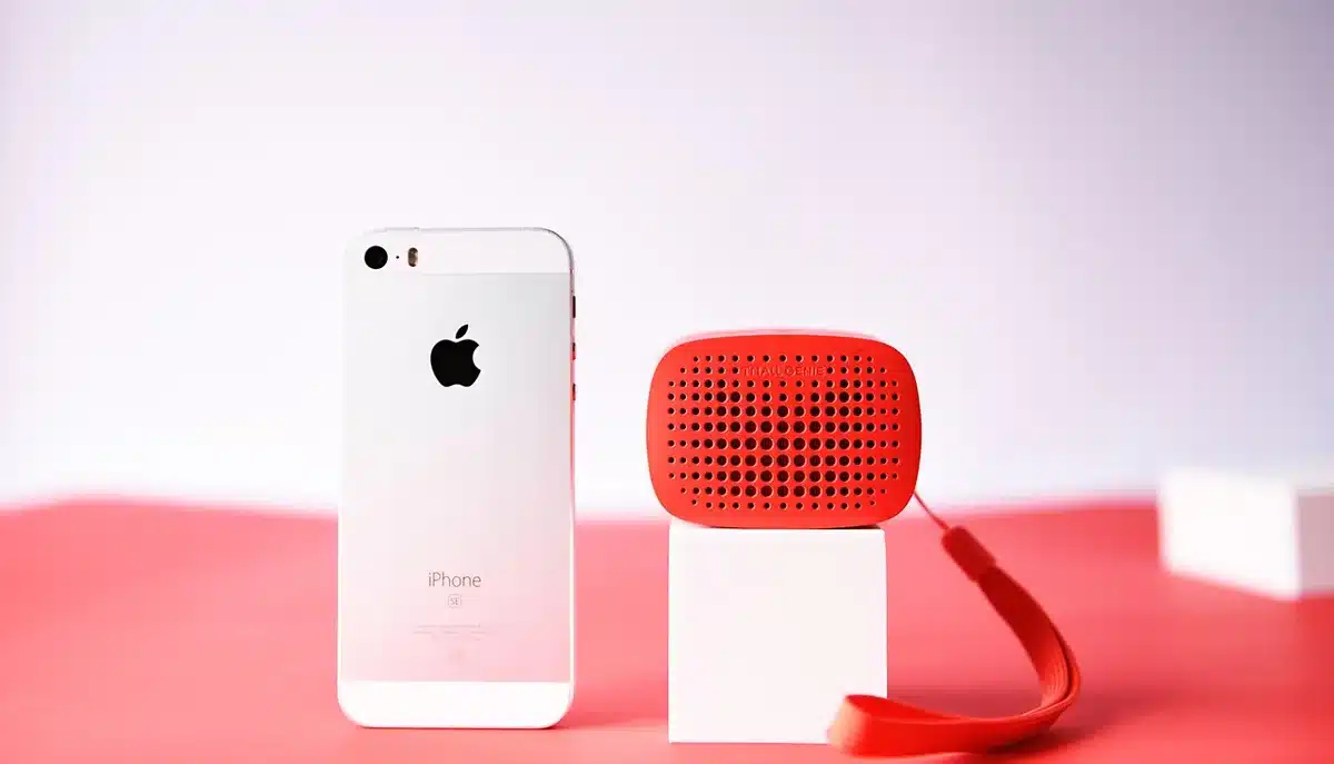 Muted smart speaker and glowing smartphone on a coffee table, distant silhouettes in a living room
