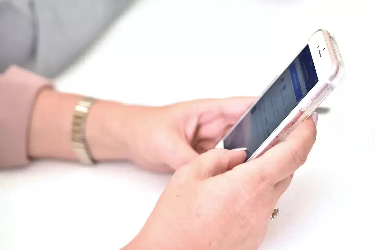 Main tenant un smartphone montrant les paramètres d'une application d'actualités