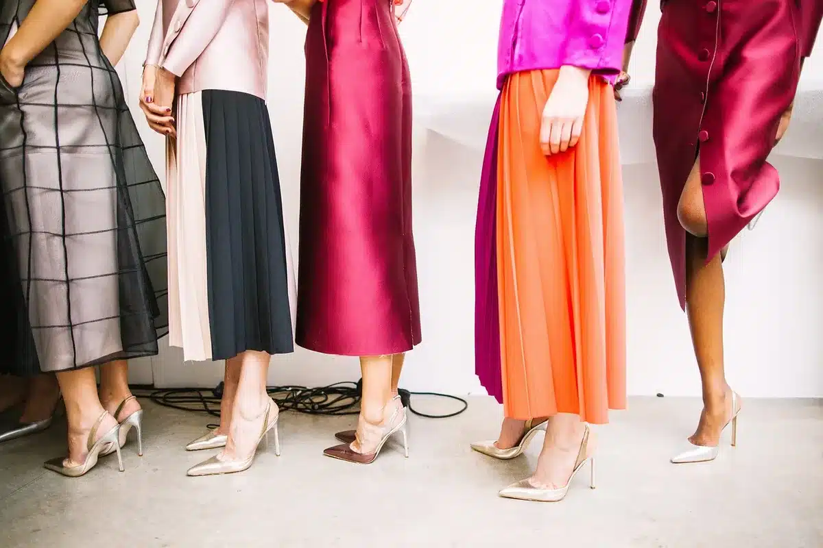 Backstage runway silhouettes with garment rack and photographers' equipment