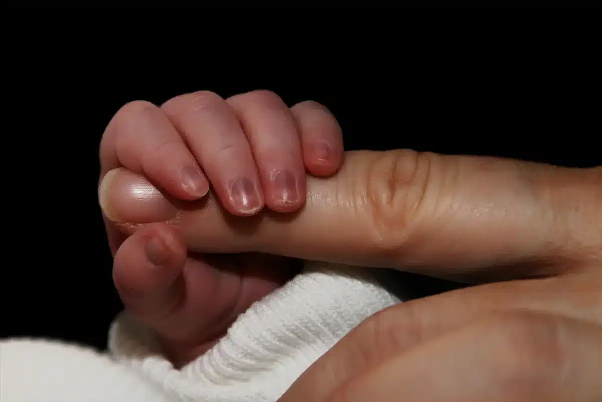 Gros plan sur la petite main d'un nouveau-né serrant le doigt d'un adulte