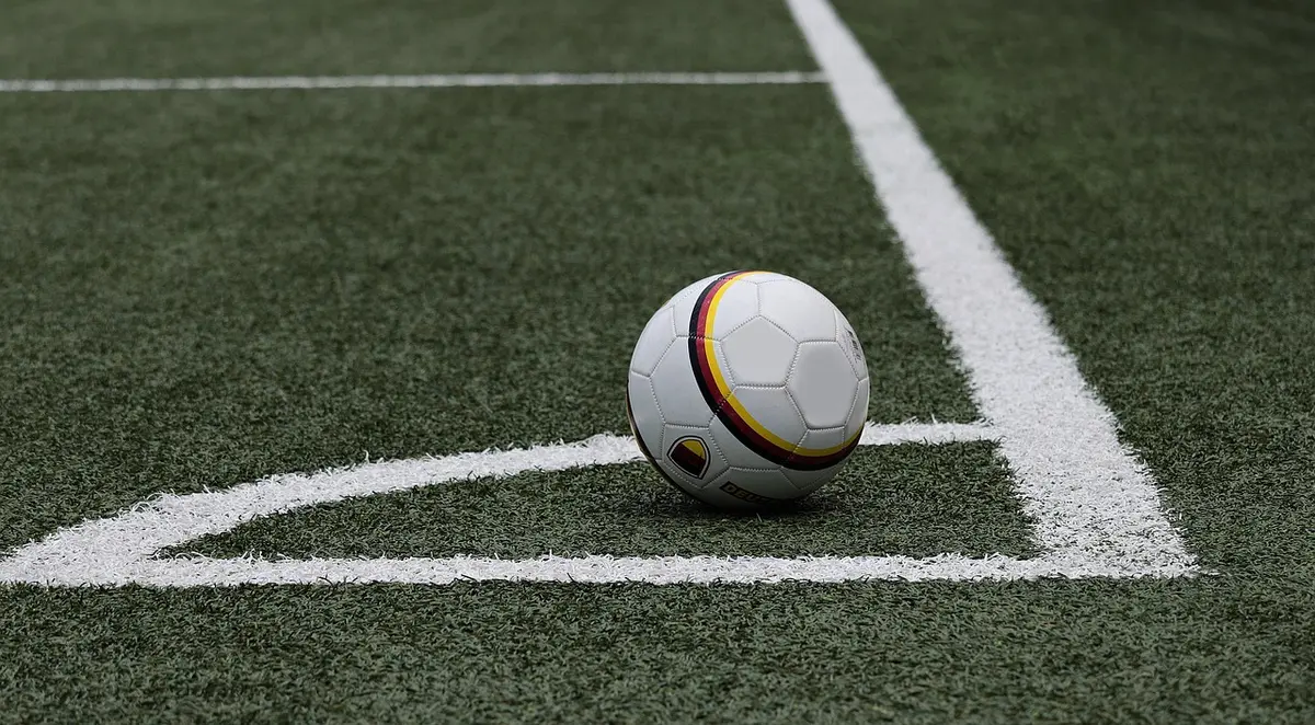 Fans and players on opposite sidelines during a daytime football game