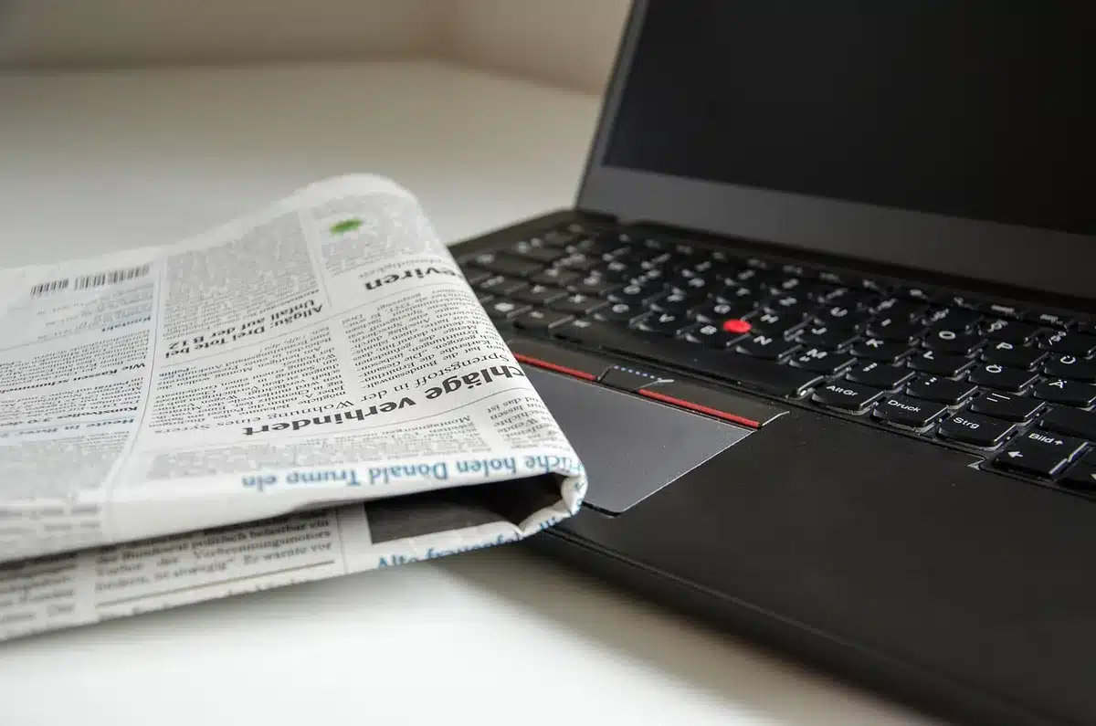 Close-up of a desk with a phone and folded newspaper reporting a death