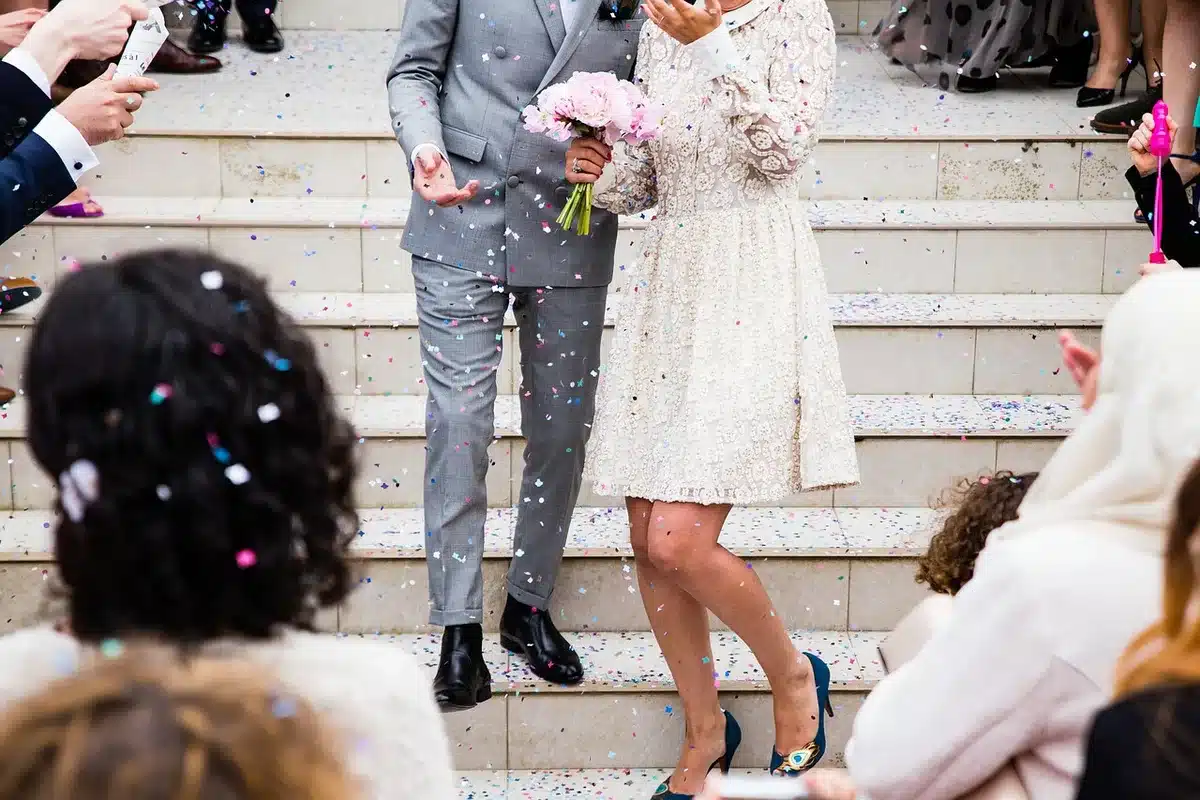 A wedding announcement card held by two hands on a table