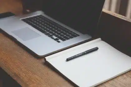 Laptop on a sunlit desk showing a webpage and a small ad-control widget, hand nearby