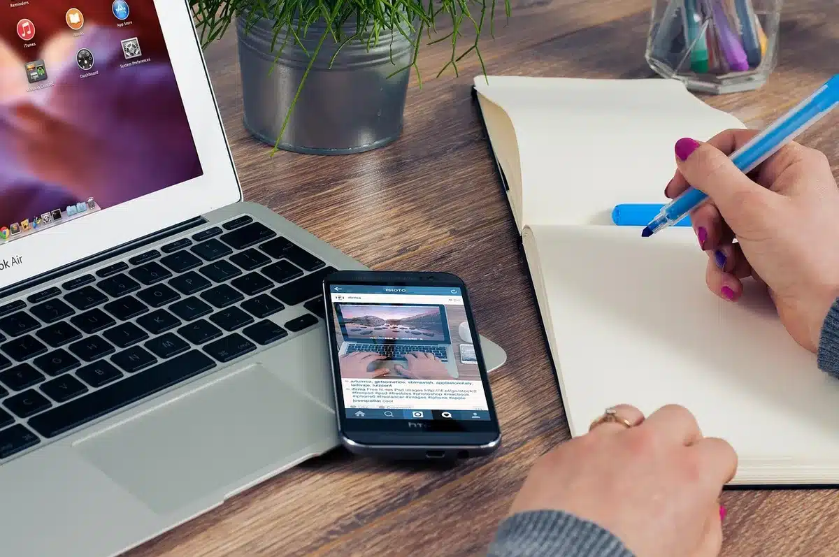 Bright home office desk with laptop and smartphone showing an email inbox